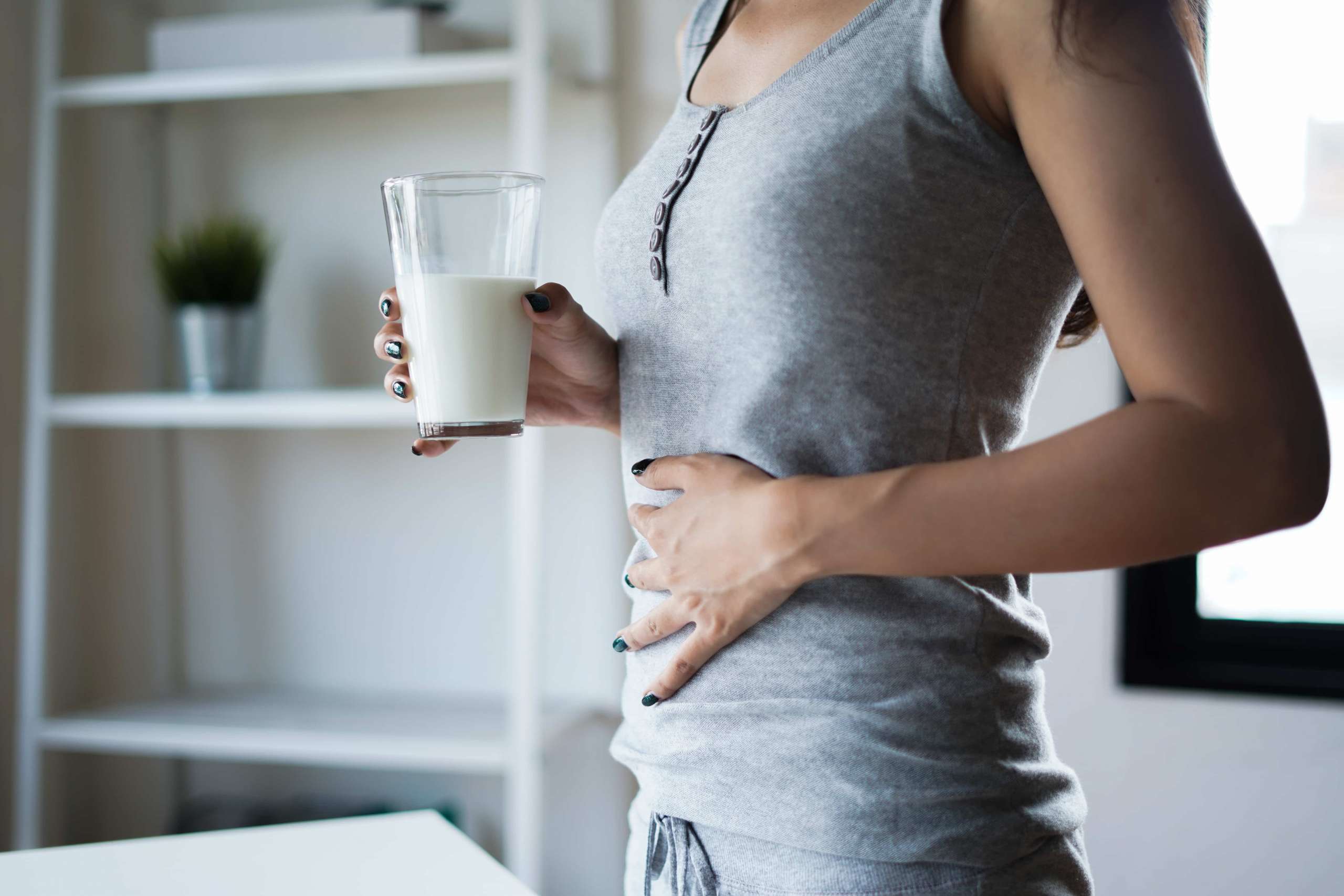 Mulher intolerância lactose segurando um copo de leite